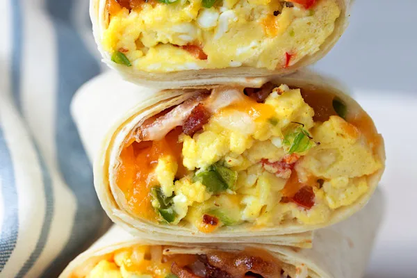 Delicious fluffy scrambled eggs, freshly sliced avocado, thick-cut crispy bacon, melted american yellow cheddar cheese, golden crisp hash brown, house-made aioli, and a hint of maple syrup, all wrapped in a warm flour tortilla.
