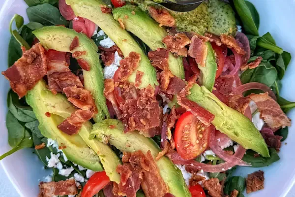 Baby spinach, arugula, pickled red onions, tomatoes, feta cheese, avocado, bacon, cilantro lime vinaigrette dressing on the side.