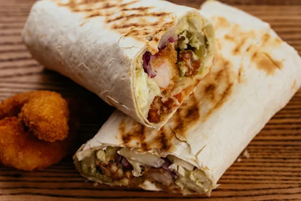 Savor the delicious flavors of our flame-broiled, hand-carved gyro nestled in a soft flour tortilla, with creamy house-made tzatziki sauce. Freshly sliced tomatoes, crisp thinly sliced red onions, refreshing organic cucumbers, feta cheese, briny Kalamata olives, and crunchy romaine lettuce, this wrap is a Mediterranean delight in every bite.