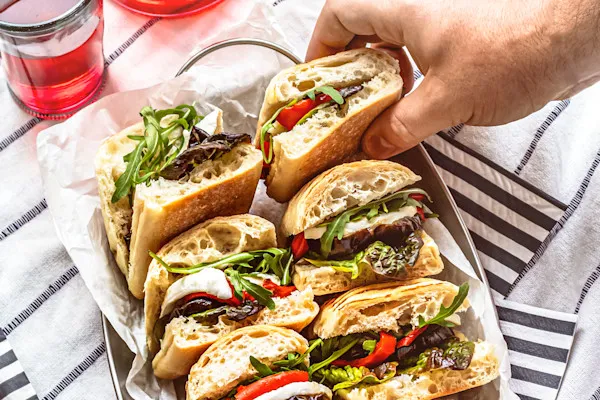 Each half sandwich is packed with crisp organic English cucumbers, juicy sliced tomatoes, house-made pickled onions, sliced pepper jack cheese, slow roasted red bell peppers, fresh baby sprouts, and creamy slices of freshly cut avocado. Finished with our signature house-made garlic aioli and a drizzle of balsamic glaze and Italian dressing on a freshly baked hoagie roll.