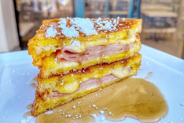 Savory grilled smoked ham, havarti cheese, mustard, mayo, on egg batter-dipped, white bread, pan fried, garnished with powdered sugar and a side of maple syrup.