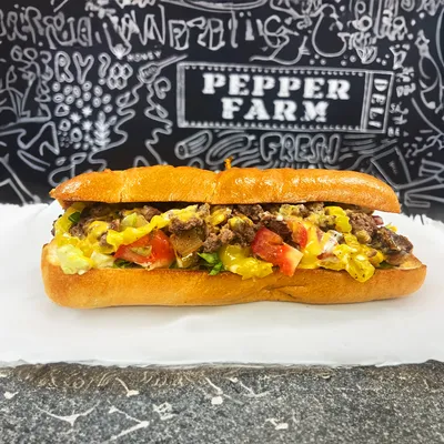 Chopped rib eye steak, grilled onions, grilled banana peppers, shredded romaine lettuce, chopped Roma tomatoes, garlic aioli, and Vermont cheddar cheese on a hoagie roll