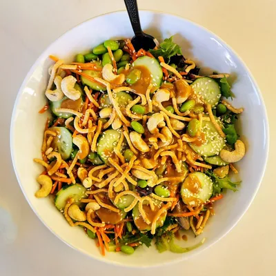Baby spring mix, edamame, crunchy matchstick carrots, cucumbers, toasted cashews, green onions, sesame seeds, cilantro, and crispy chow mein noodles served with our homemade dressing.