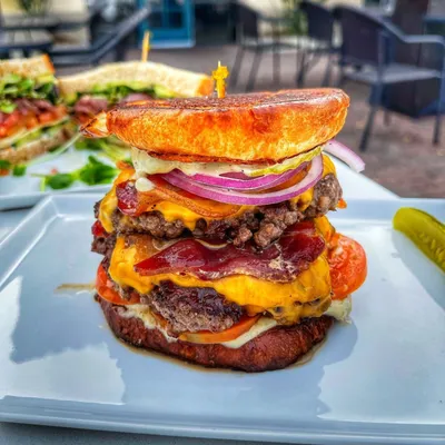 Two 100% rib eye beef patties ground and hand patted on premises, Vermont cheddar cheese, Boar’s Head thick cut bacon, Roma tomatoes, thinly sliced onions, Boar’s Dill pickle chips, peppercorn aioli on a toasted and buttered Brioche bun