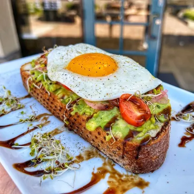 Thinly sliced avocado, sunny-side up egg, pickled red onions, sprouts, balsamic glaze, on rustic sourdough bread.