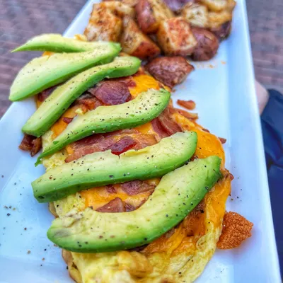 Eggs, grilled smoked applewood thick-cut bacon, freshly sliced avocado, yellow cheddar cheese with your choice of toast and your choice of side item (hash-browns, skillet potatoes or fruit)