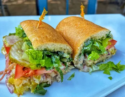 Chopped grilled chicken, grilled onions, banana peppers, shredded romaine, chopped roma tomatoes, garlic aioli, diced pickles, and melted white cheddar cheese on a hoagie roll.