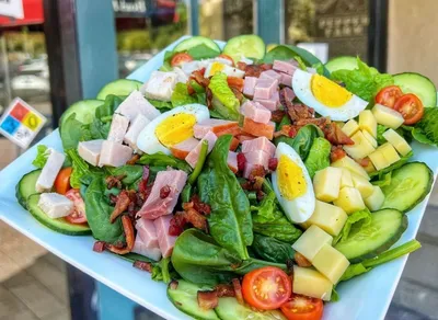 Romaine lettuce and baby spinach, cucumbers, heirloom tomatoes, turkey breast, ham, bacon, sliced hard-boiled eggs, swiss cheese, house ranch dressing on the side.